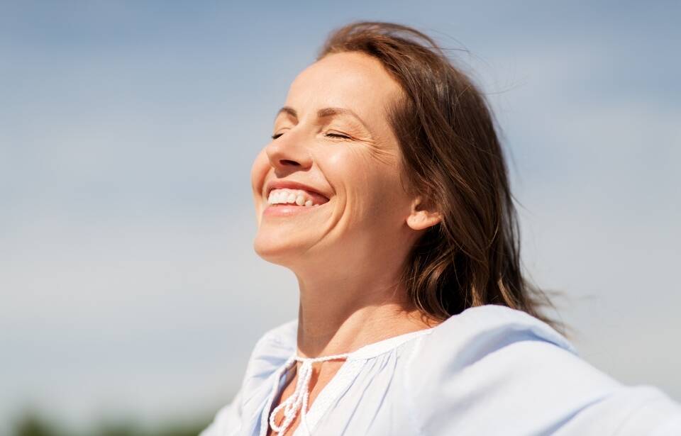 a woman smiling as the sun hits her face