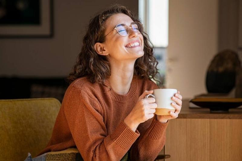 A woman smiling with a cup of coffee in her hand