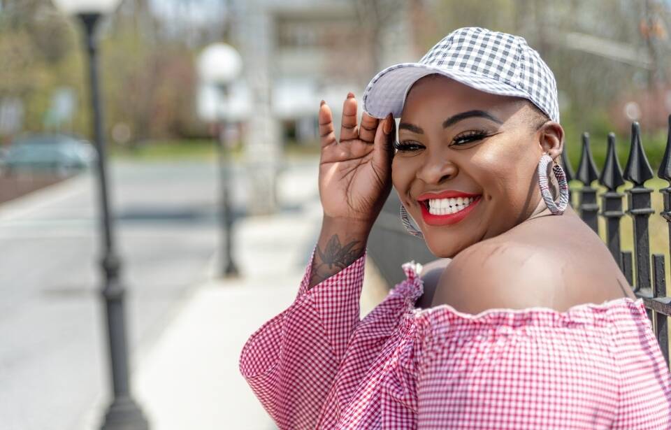 A smiling woman tipping her hat to the camera