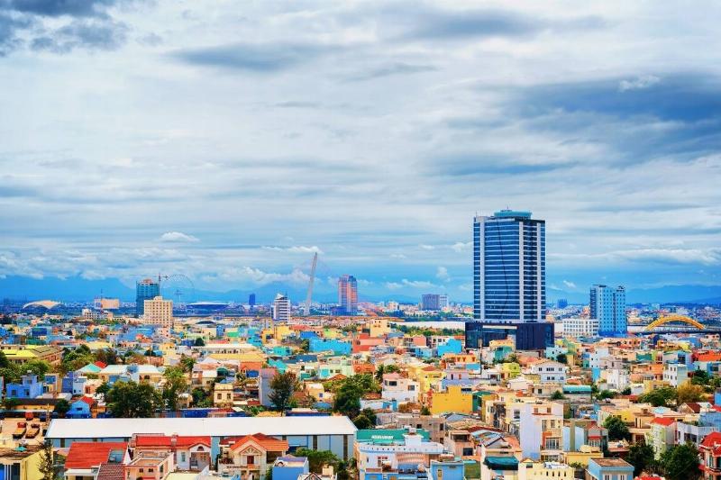 A view of a city in vietnam, with brightly coloured houses and historic buildings, as well as newer and taller skyscrapers.