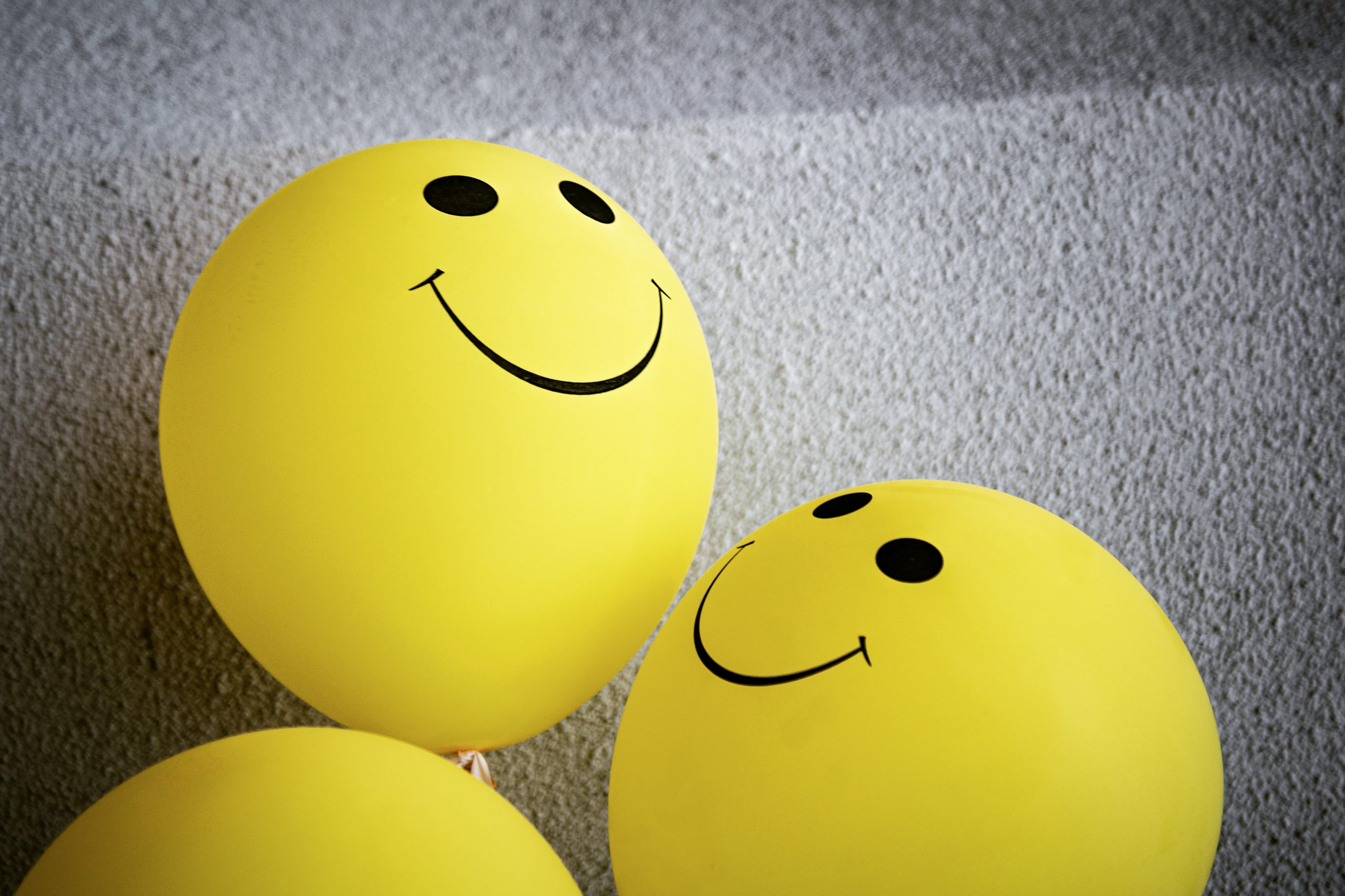 Three yellow balloons sporting happy faces.