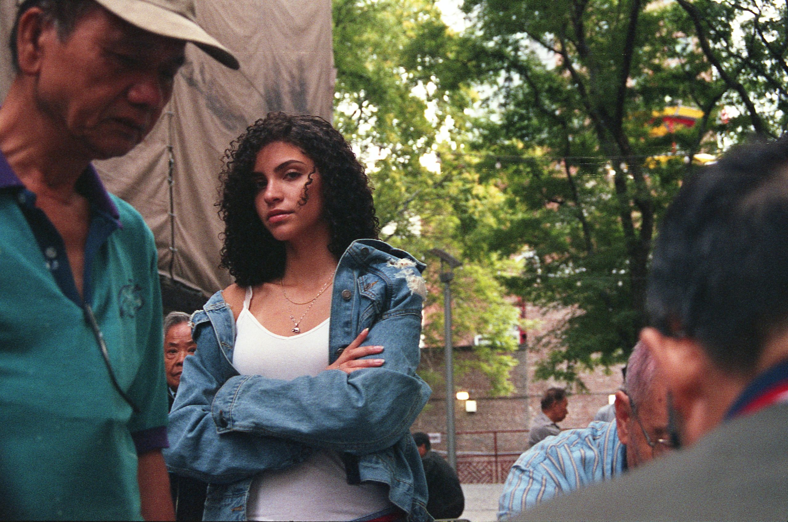 A woman with her arms folded, looking right at the camera.