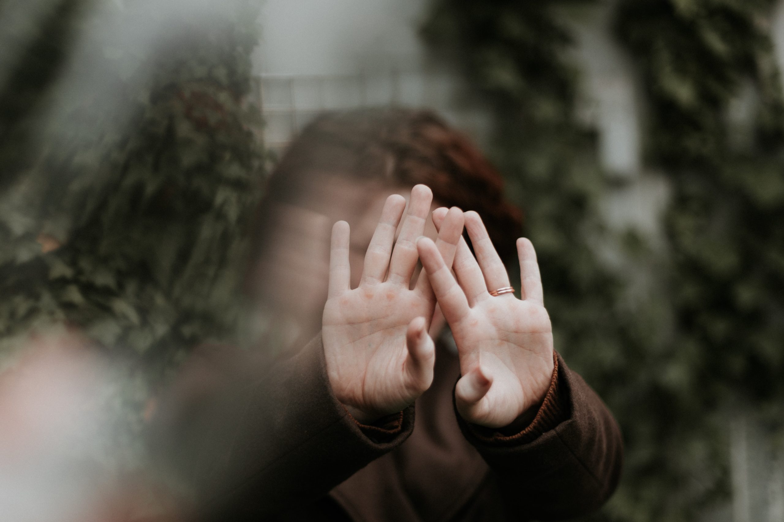 A woman holding both hands up in front of her face.