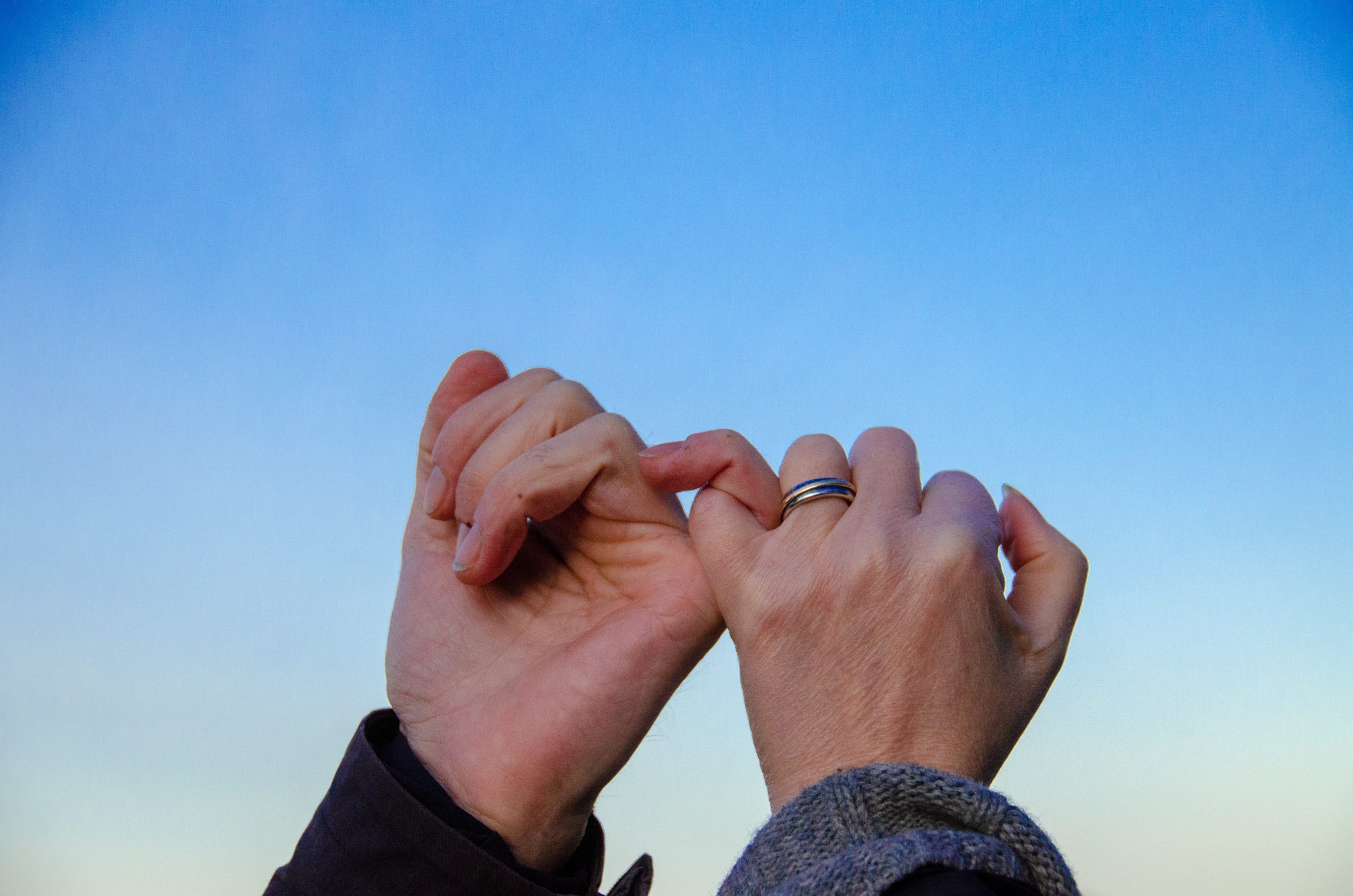 Two people locking pinkies in a promise.