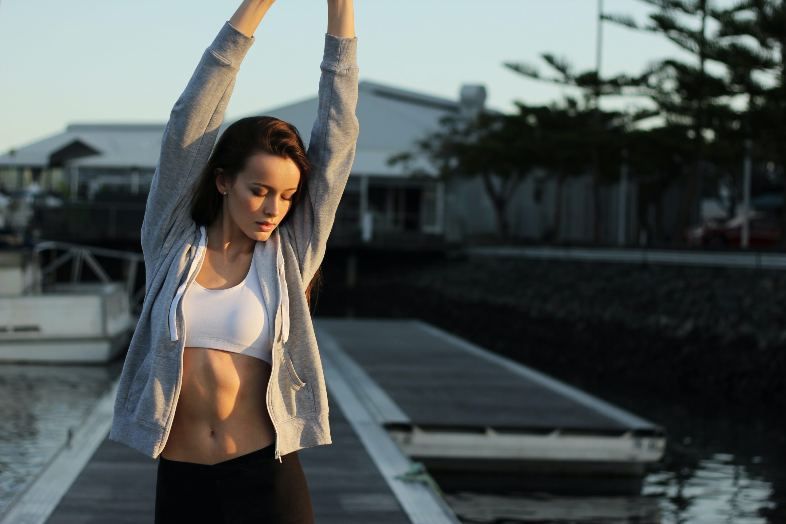 A woman stretching her arms on a boardwalk.