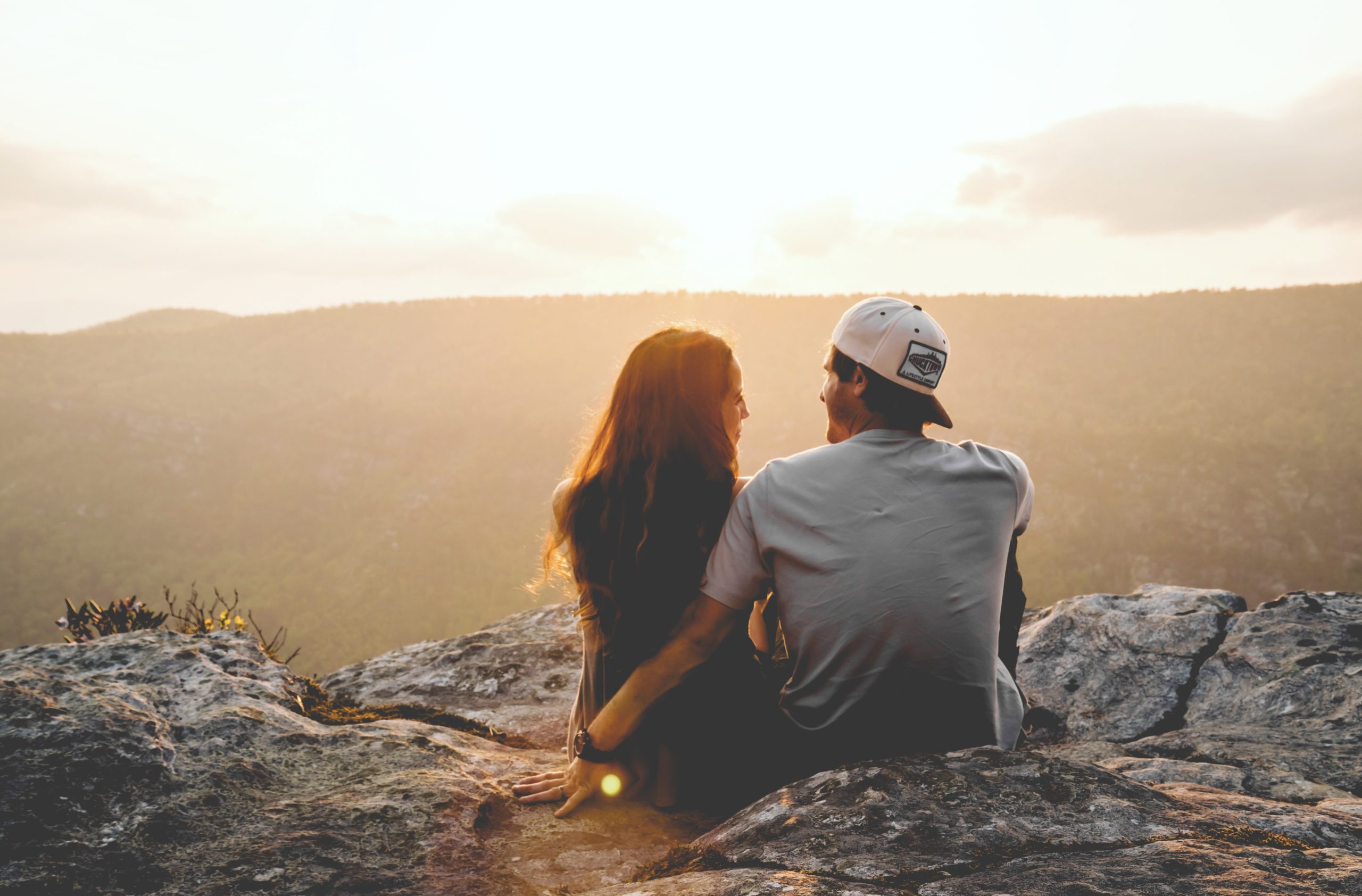 A couple sitting on a cliff's edge.