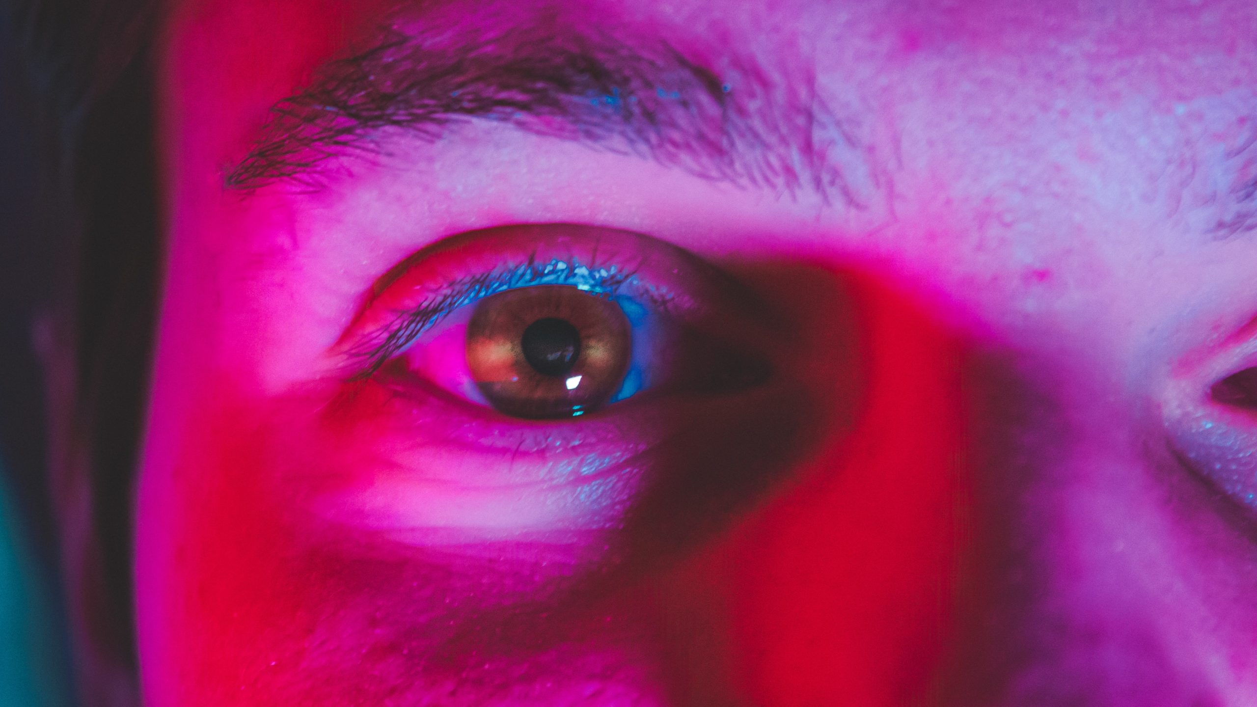 A closeup of someone's eye, lit in pink.
