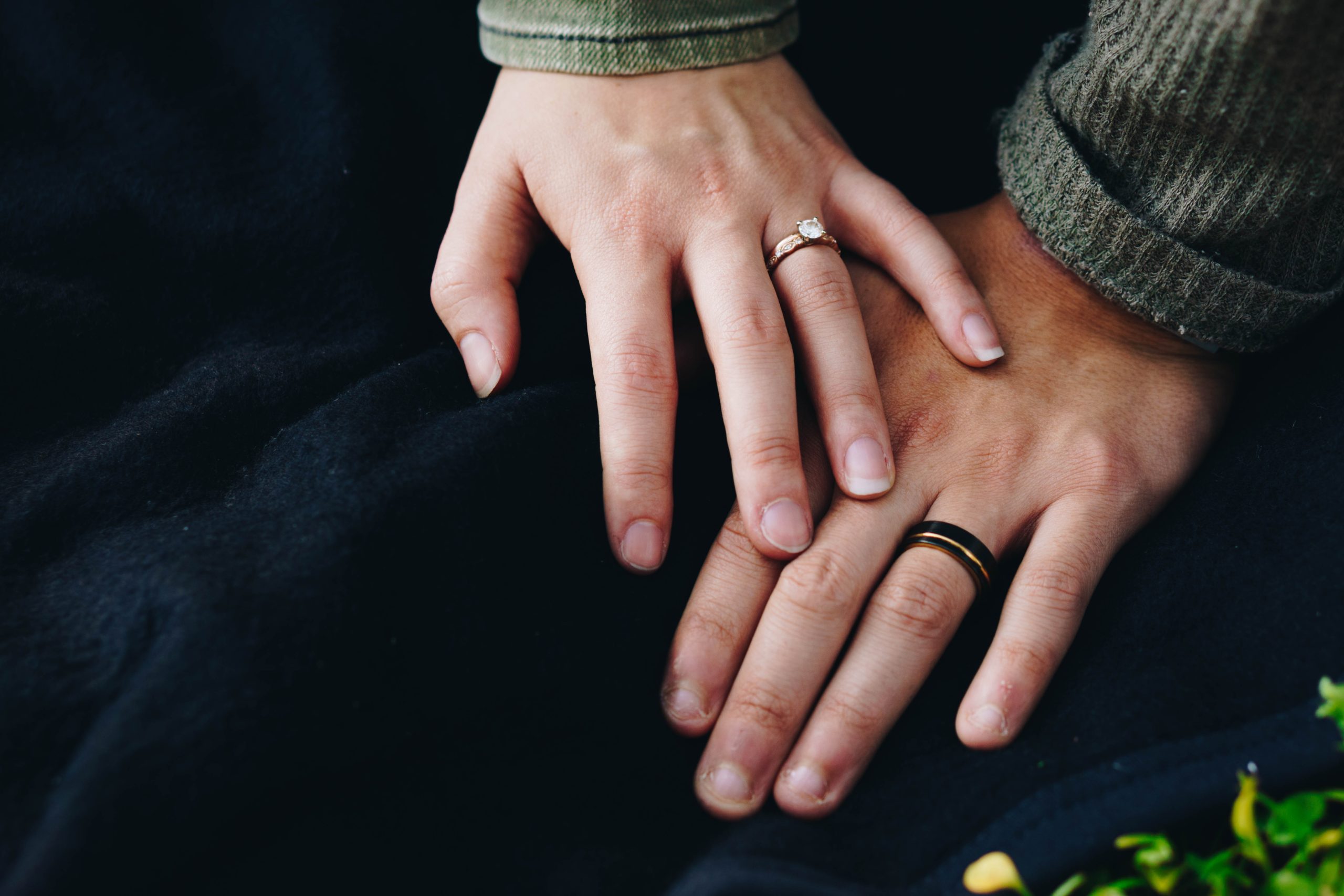 Two hands with wedding rings brushing together.