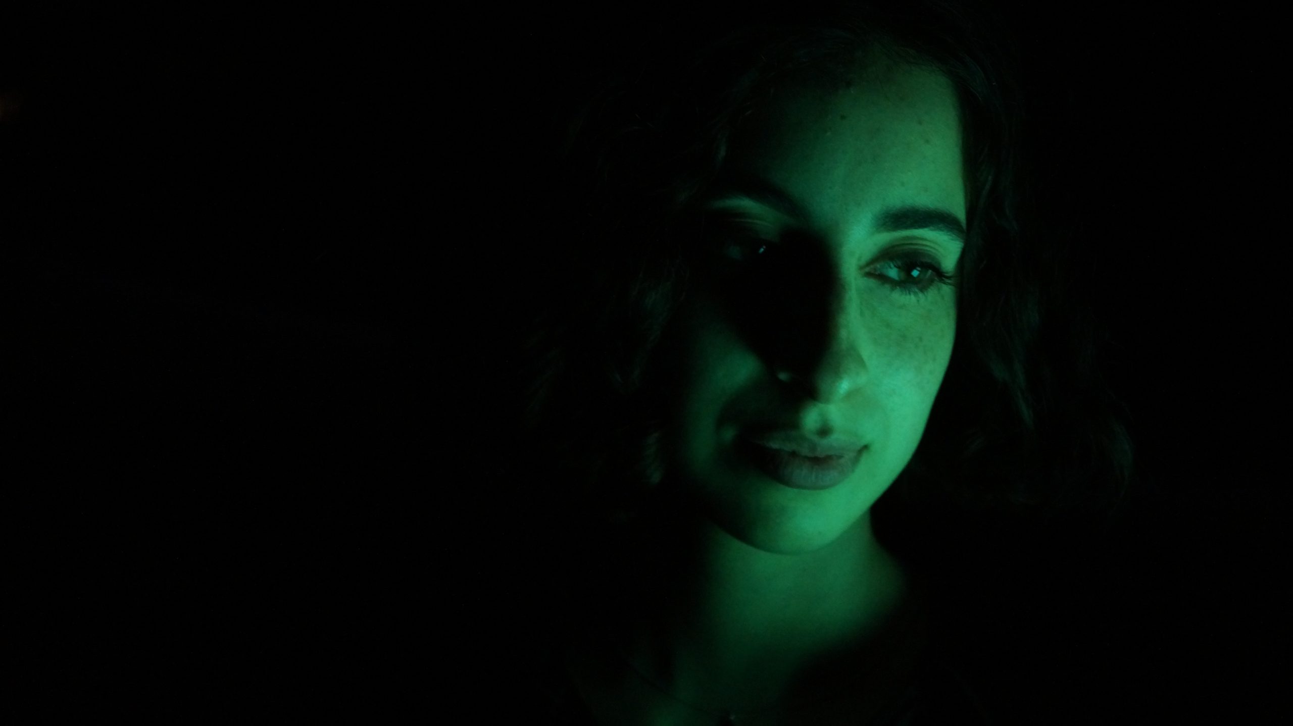 A woman's face lit in green.