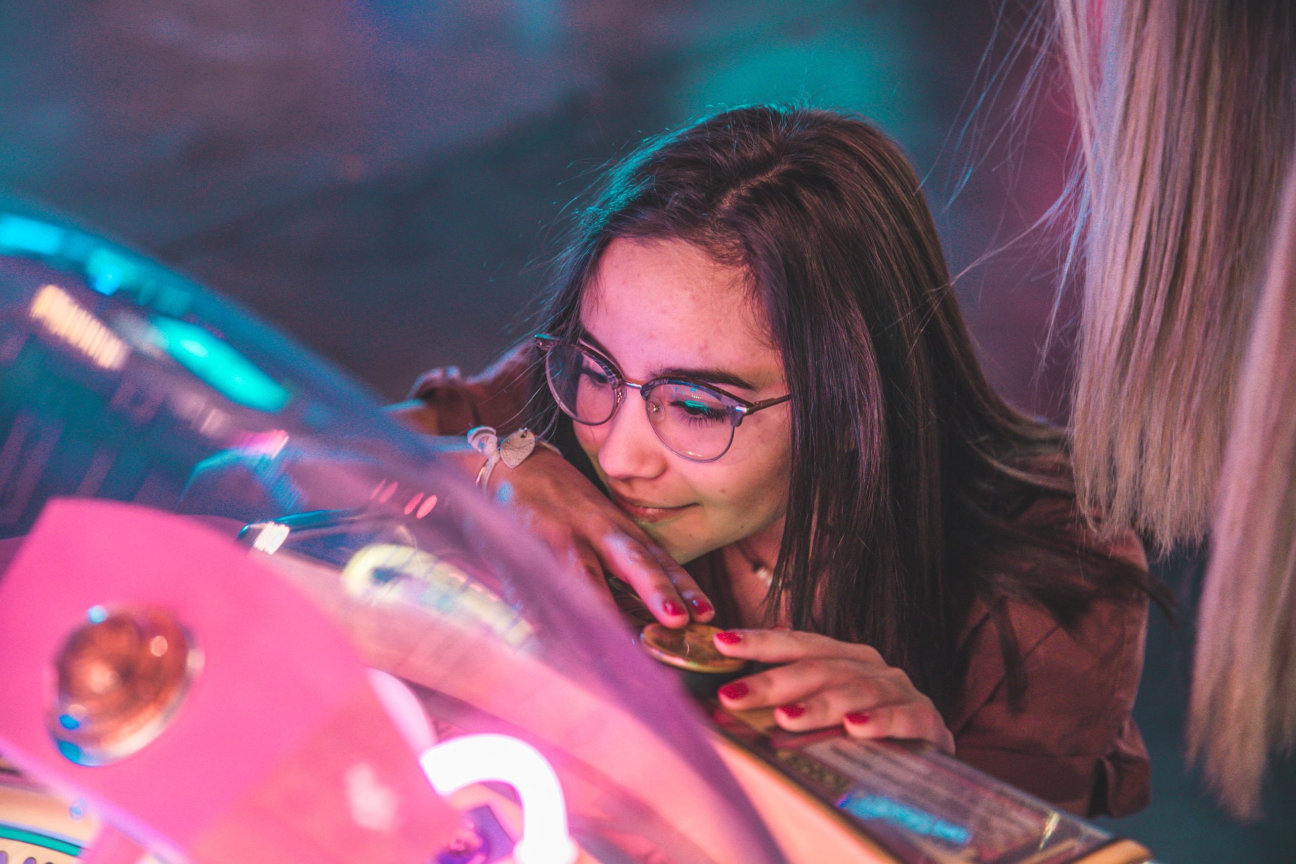 A girl closely inspecting a colorfully-lit machine.