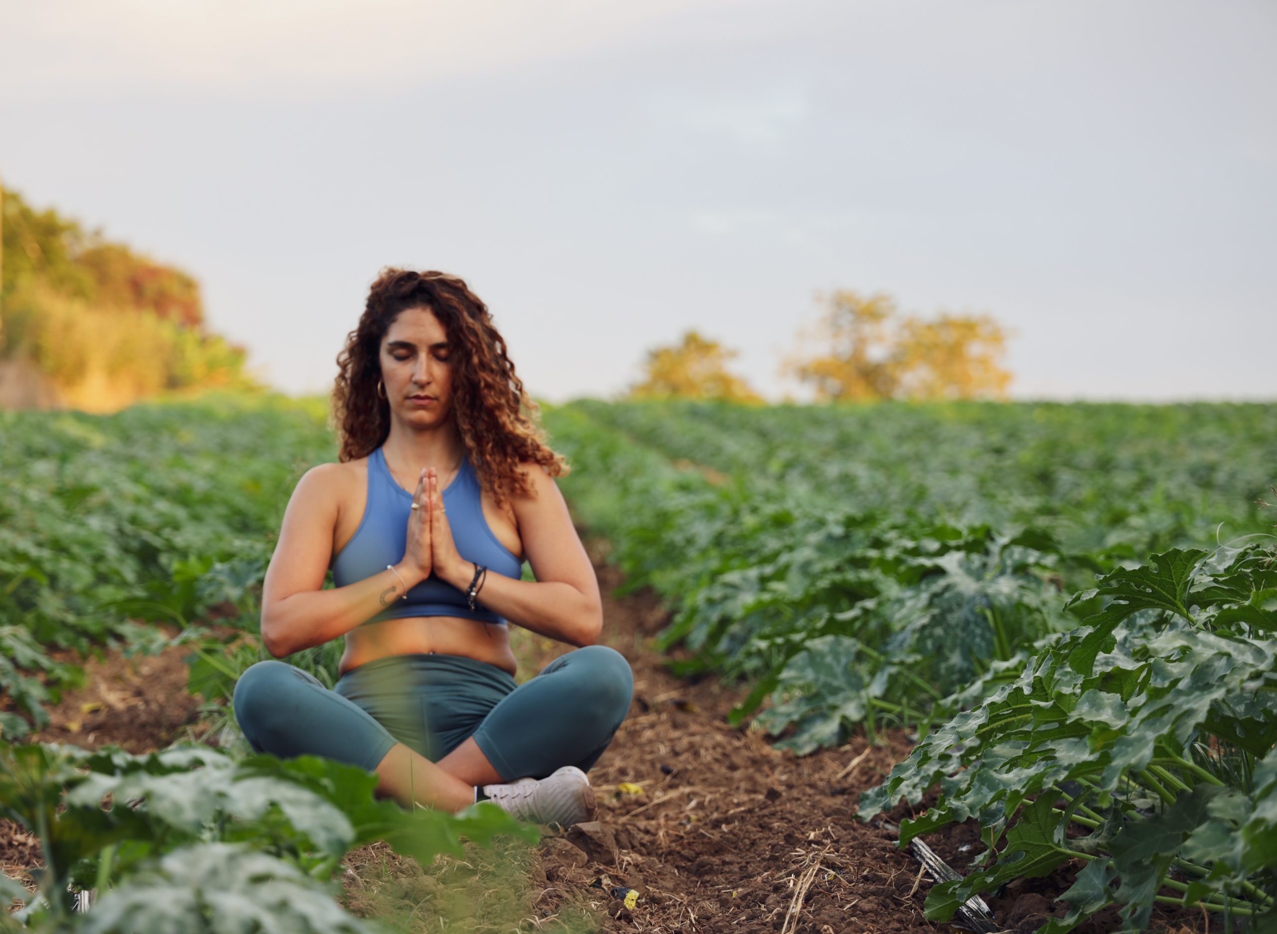 A woman sitting in a field meditating.