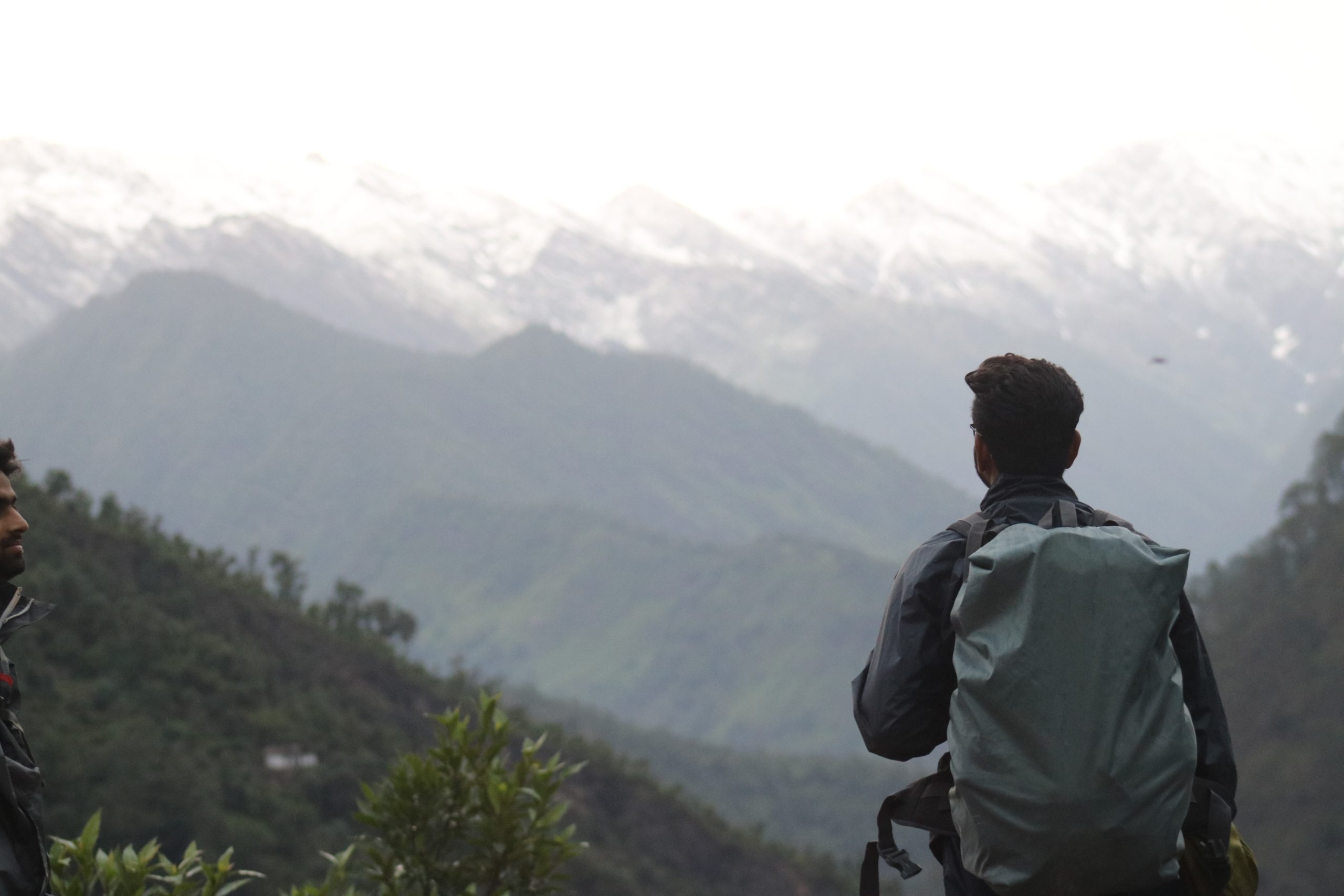 A man with a backpack staring at a foggy mountain range.