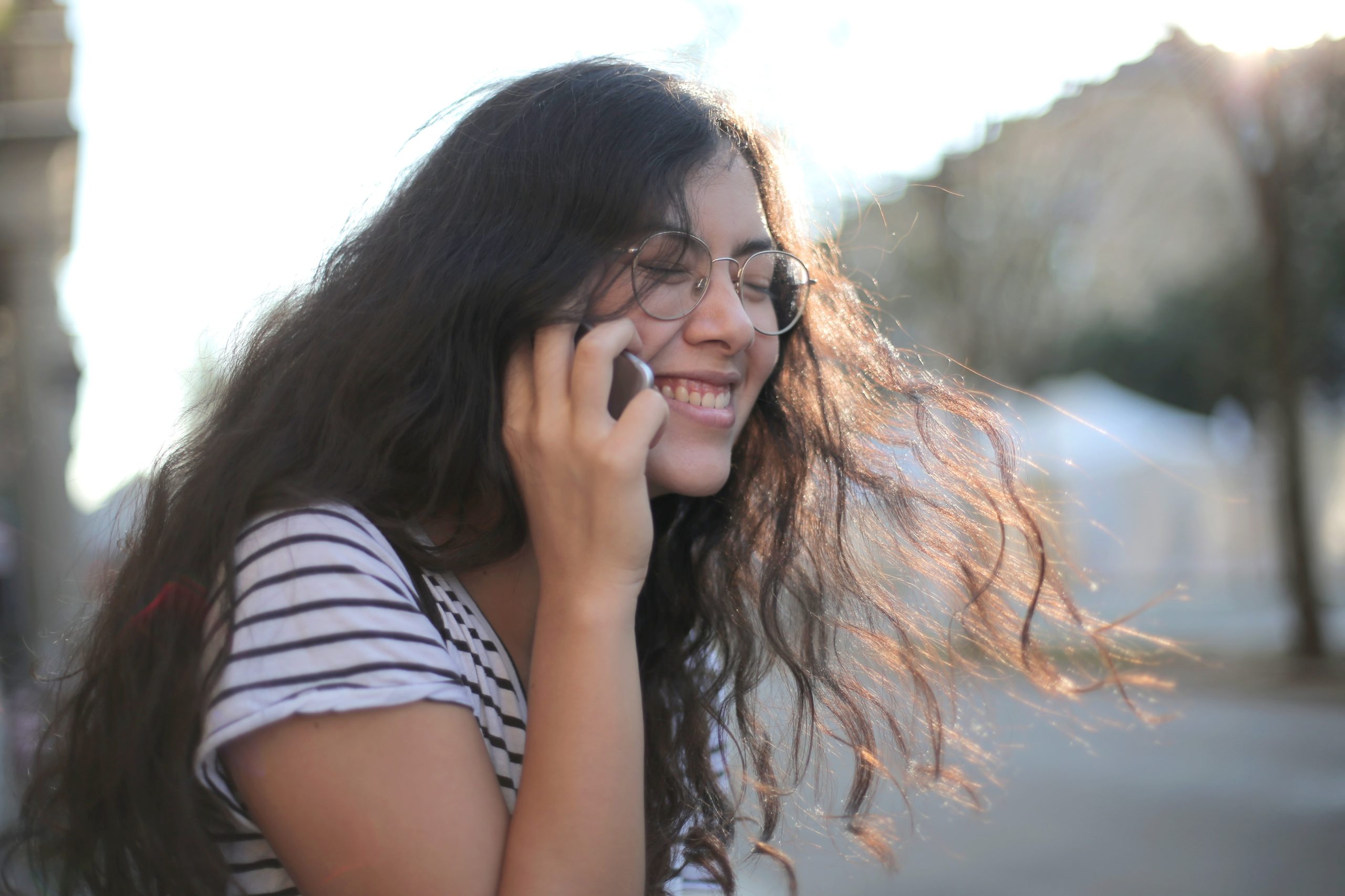 A girl smiling as she speaks on the phone.