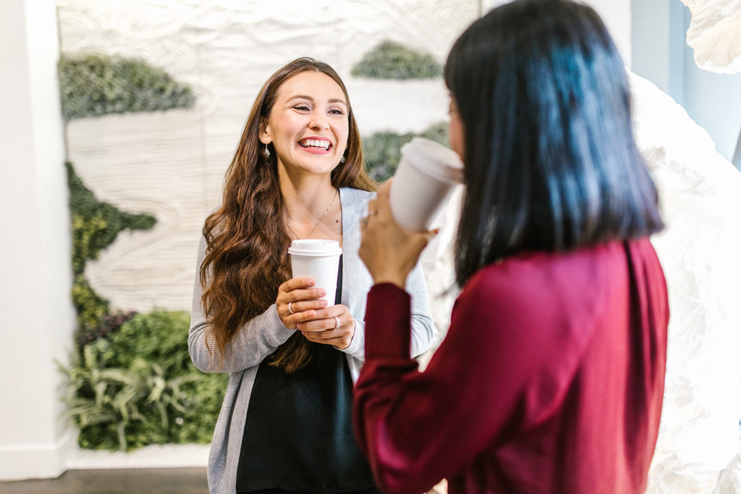Two women smiling and laughing over coffee.
