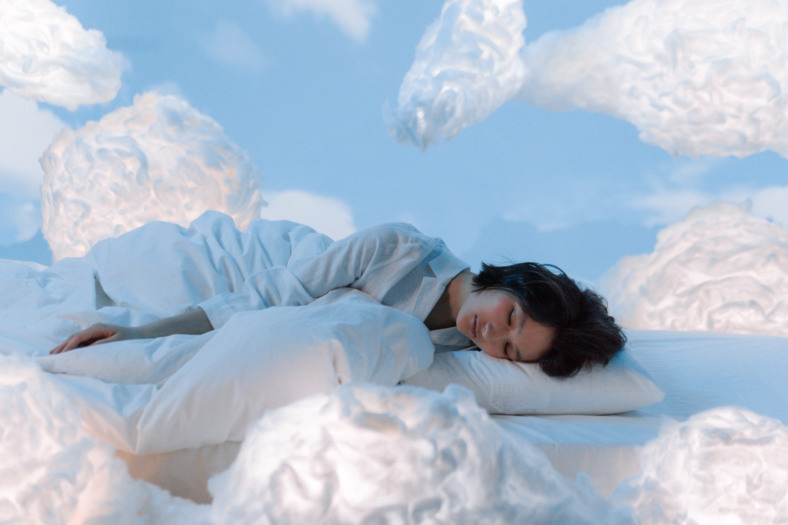 A woman asleep amid a sky of clouds.
