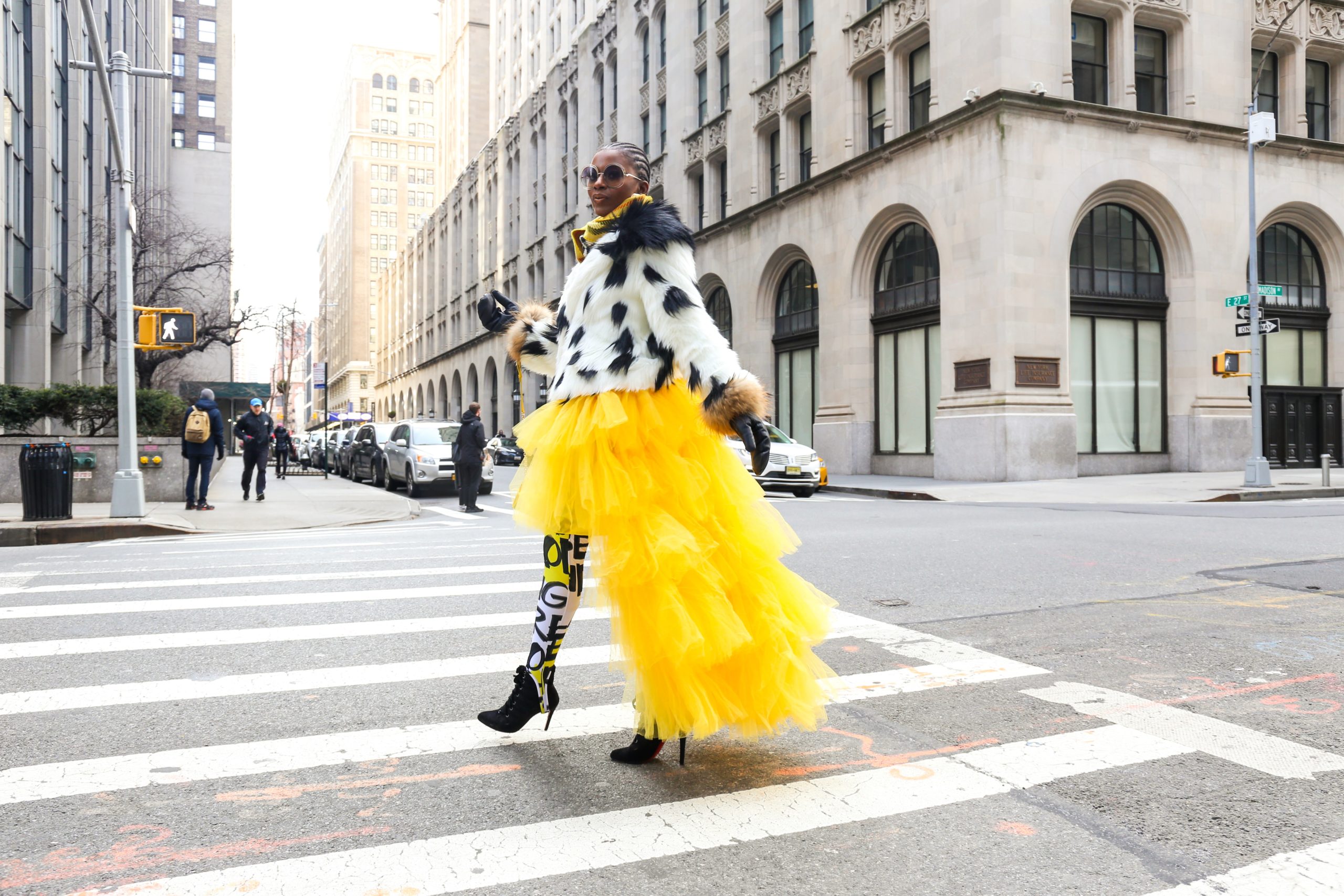 A woman waling along the street in an eccentric, high fashion outfit.