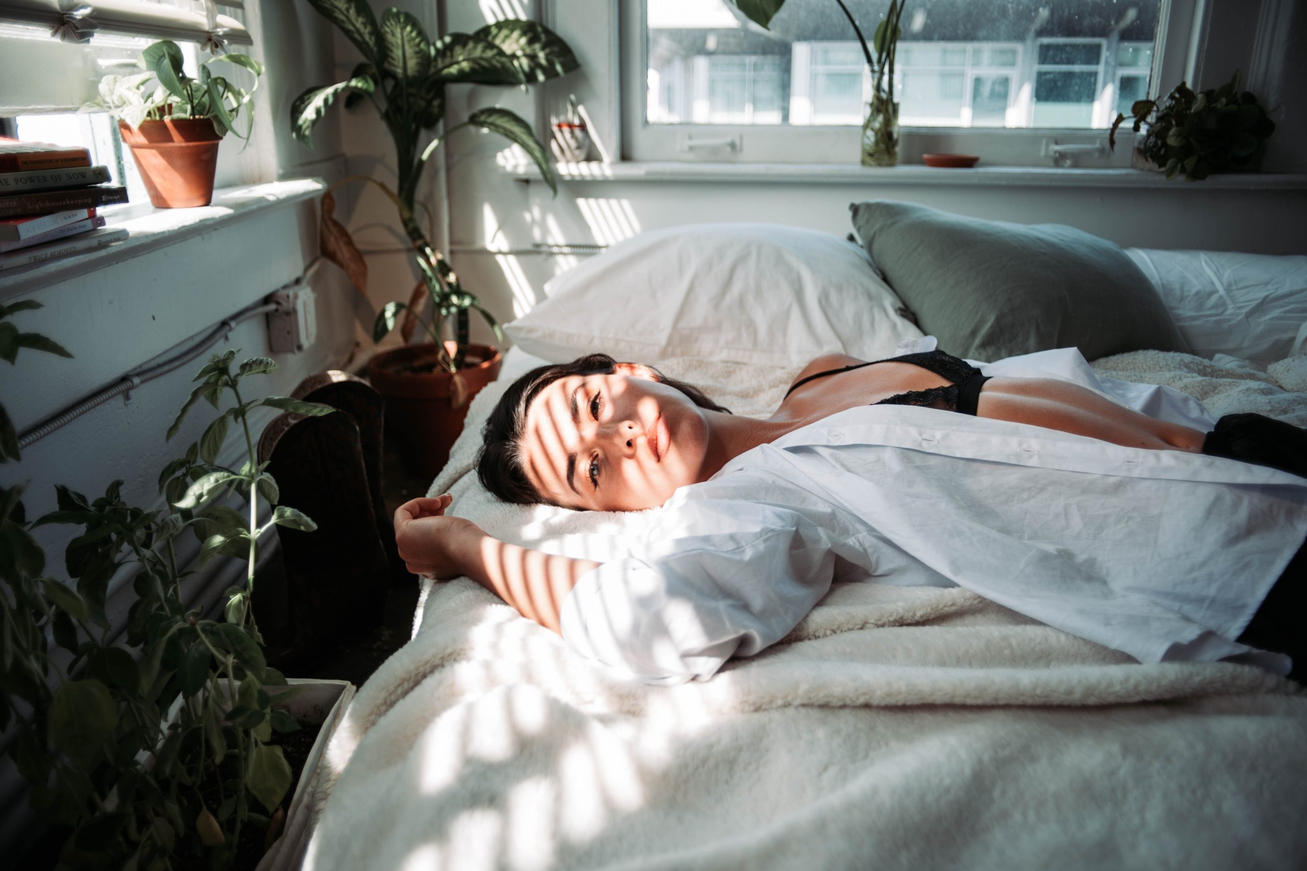 A woman laying in bed, streaks of light appearing across her face.