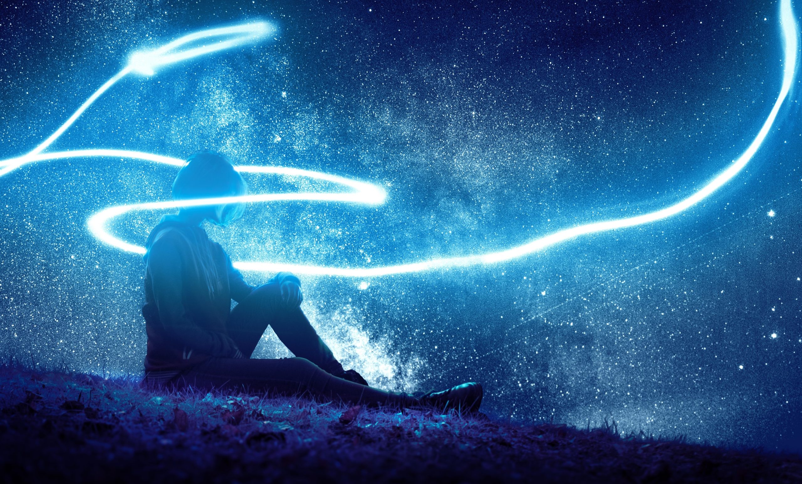 A woman seated on a hill, a blue light swirling around her.