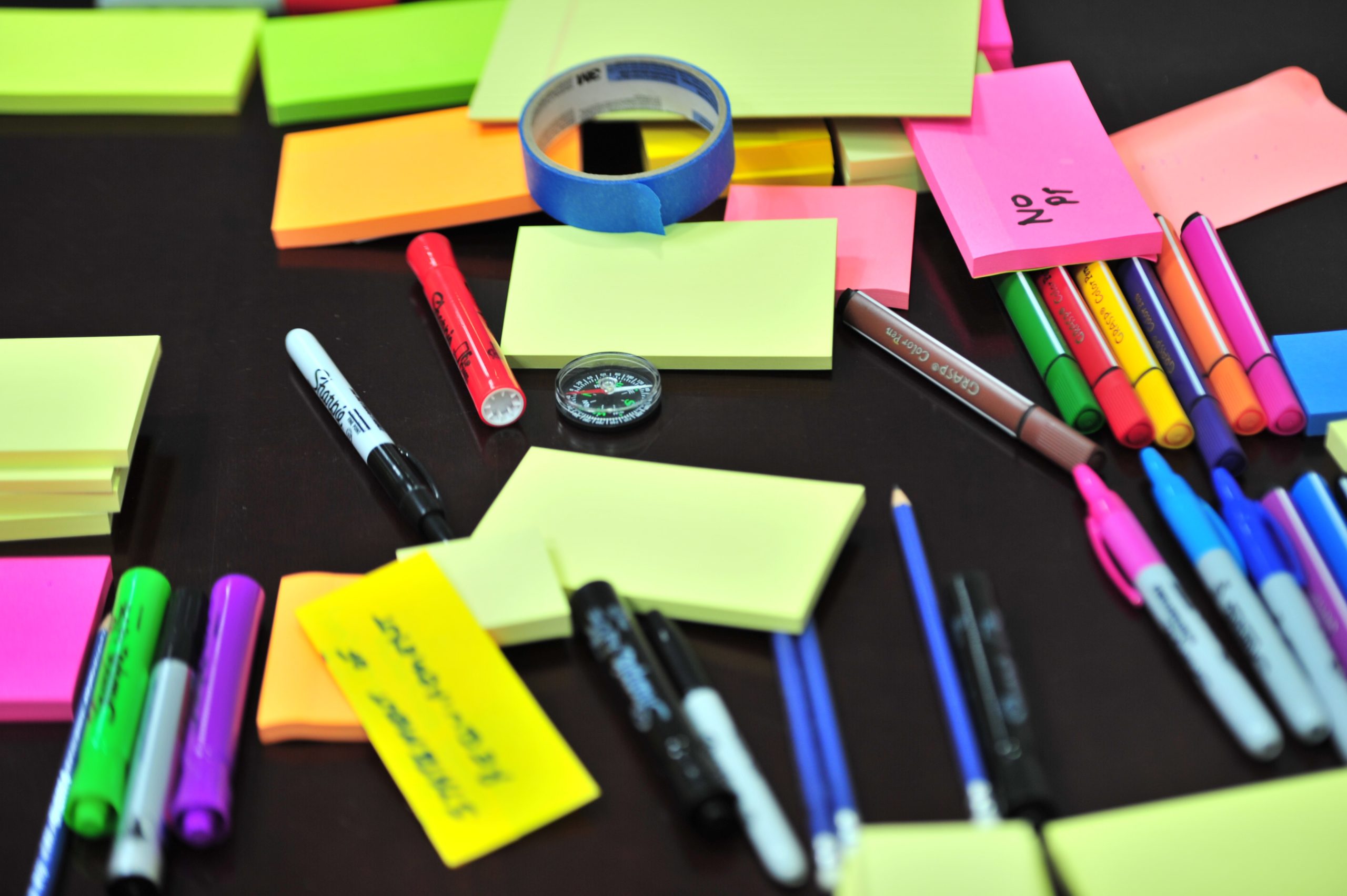 A desk scattered with colorful stationary supplies.