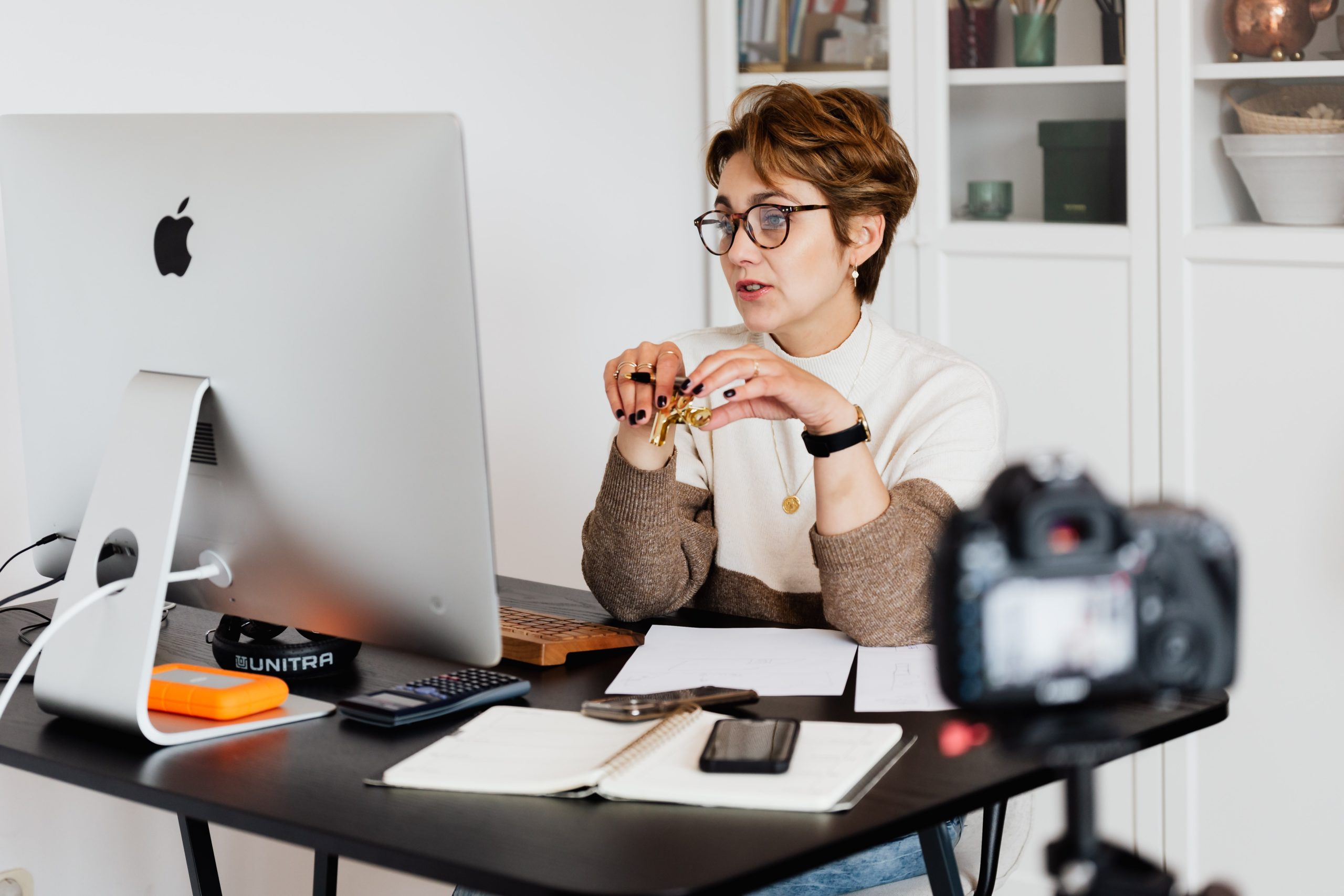 A professional woman sitting at her desk, being filmed.