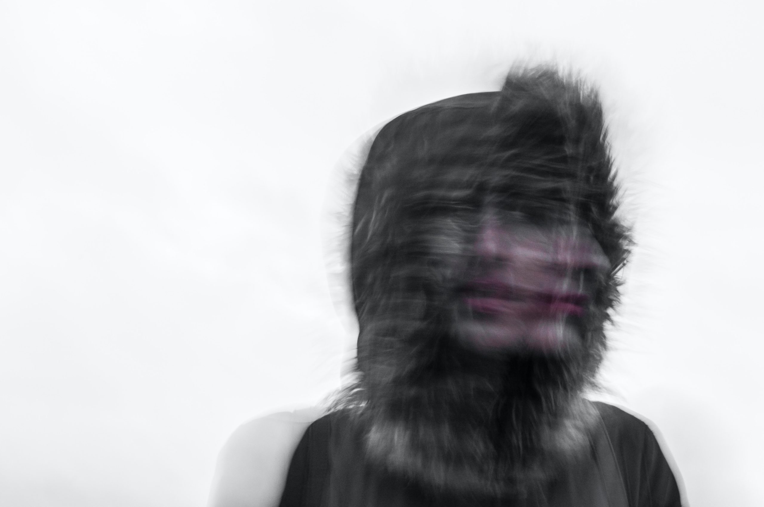 A blurry, superimposed image of a woman in a fur hood looking away.
