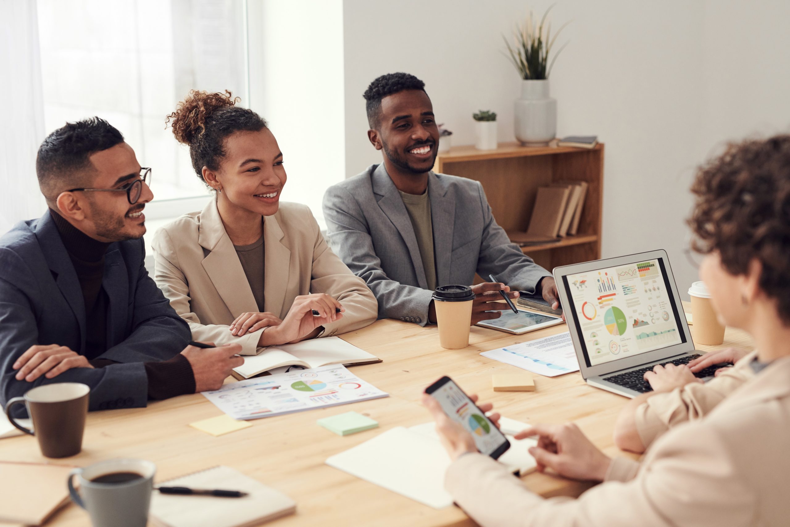 A group of young business people sitting at a desk and smiling.