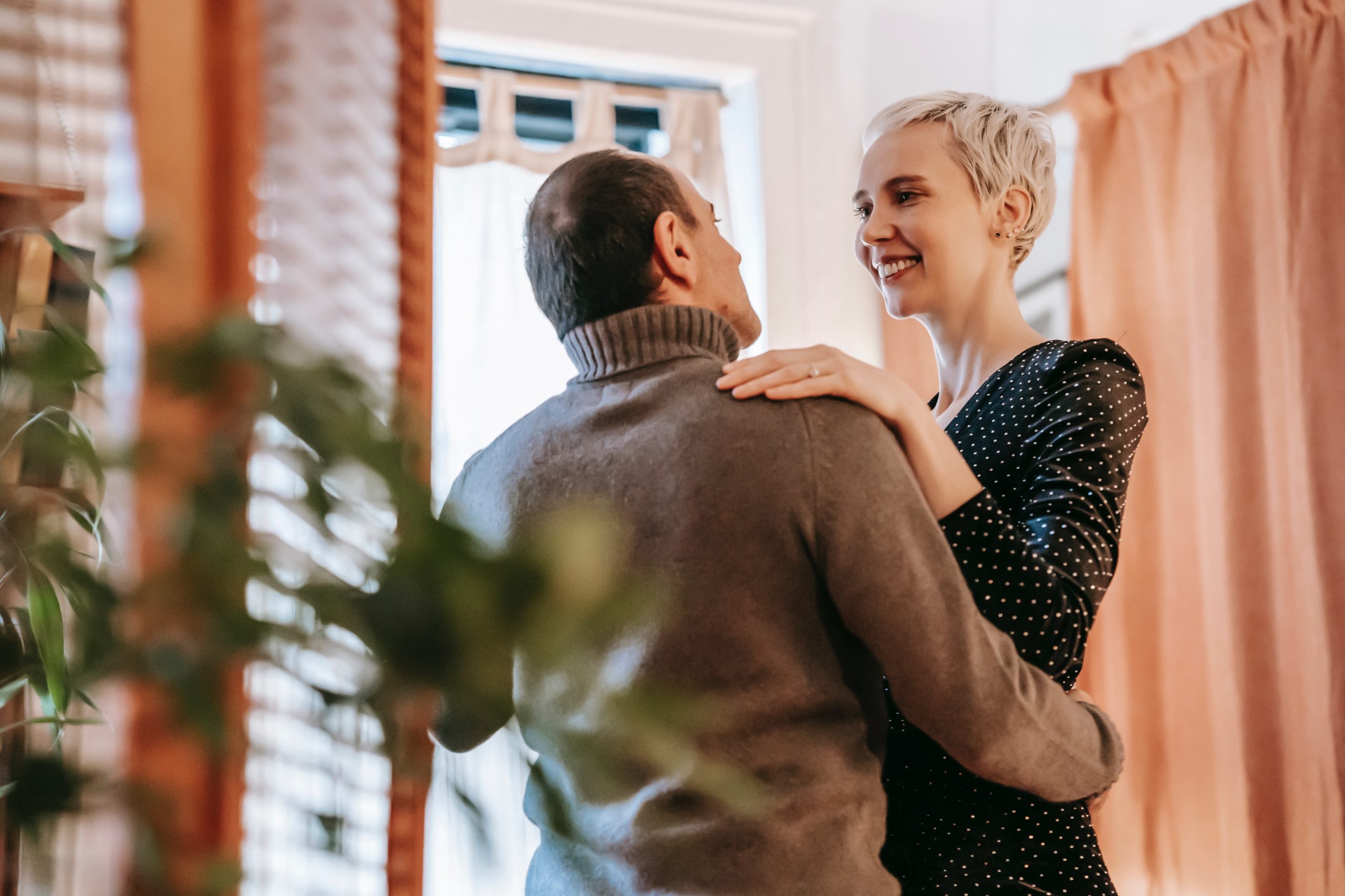 A couple slow dancing together in their living room.