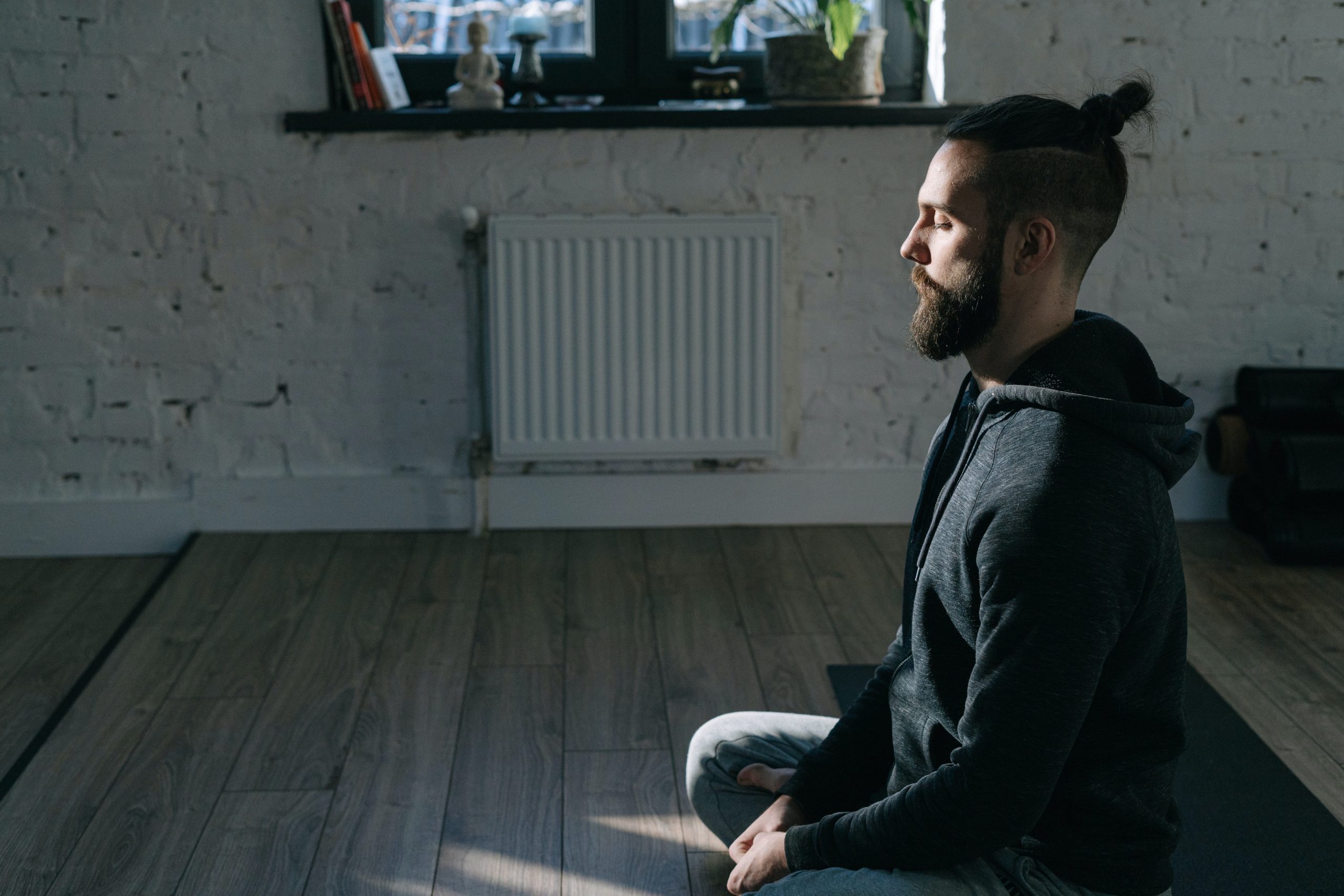 A man sitting on his floor, meditating.