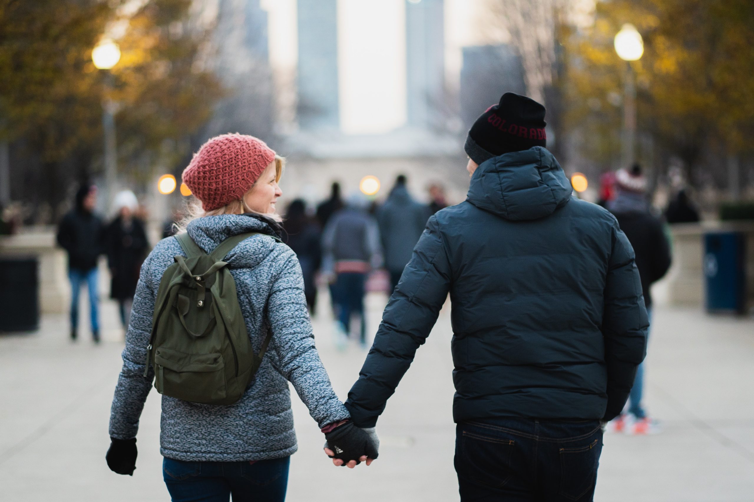 A couple in the cold, holding hands as they walk along the street.