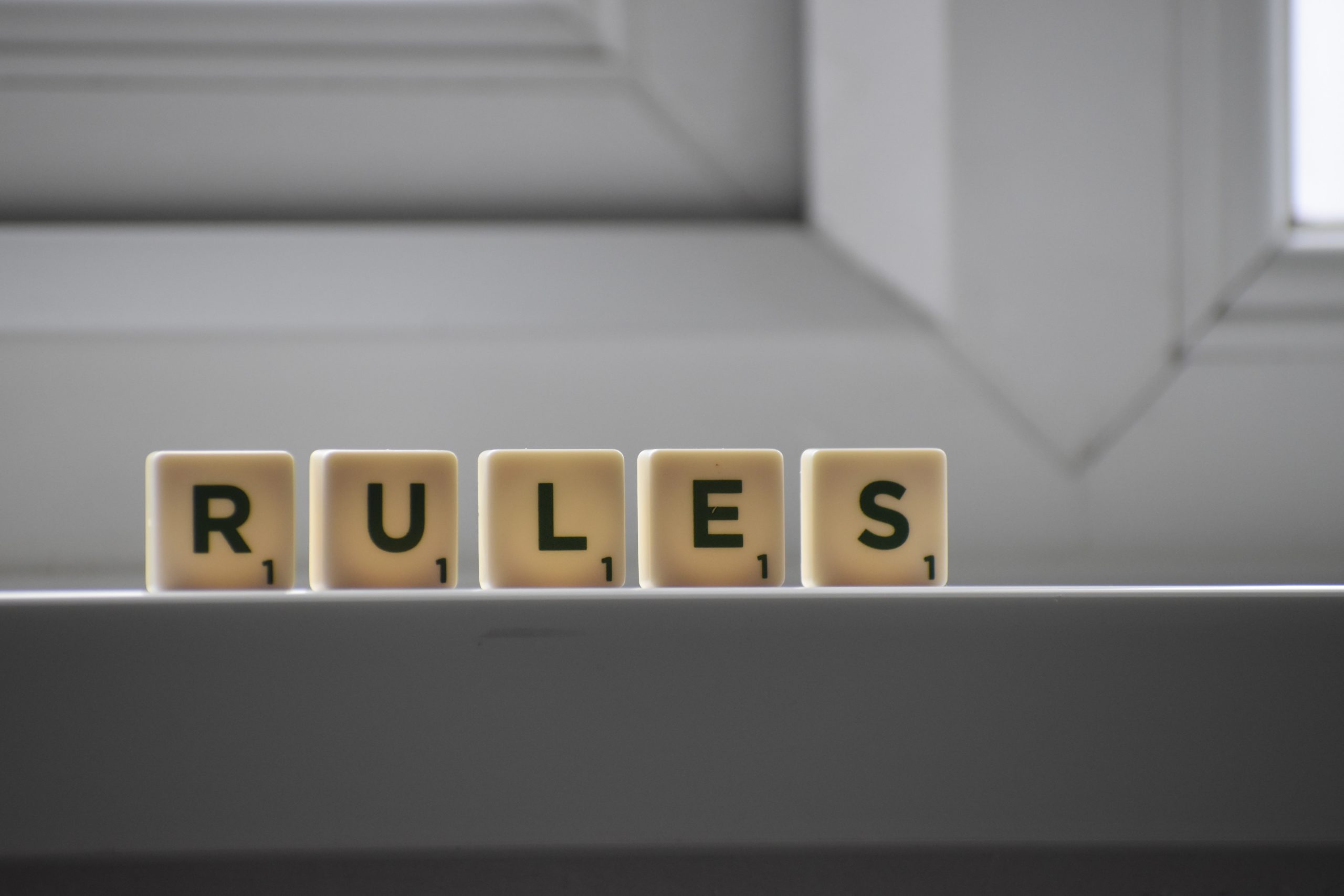 The word 'rules' spelled out in scrabble tiles on a windowsill.
