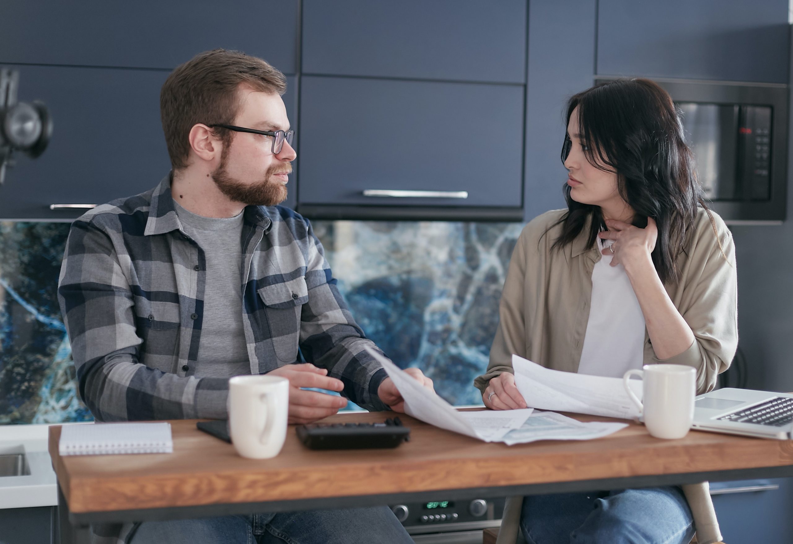 A couple sitting at a table, looking at each other with tension.