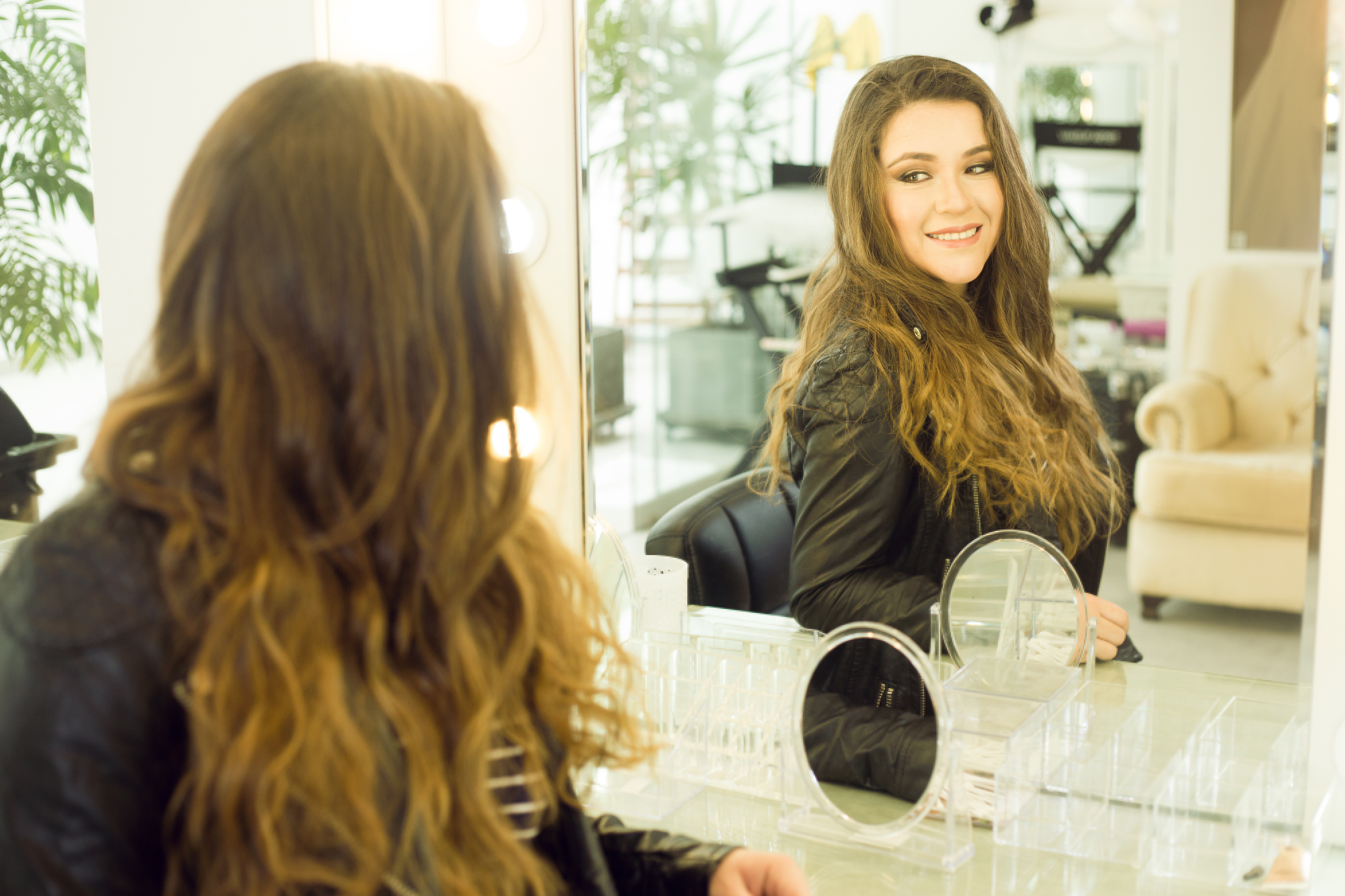 A woman looking and smiling at herself in a mirror.