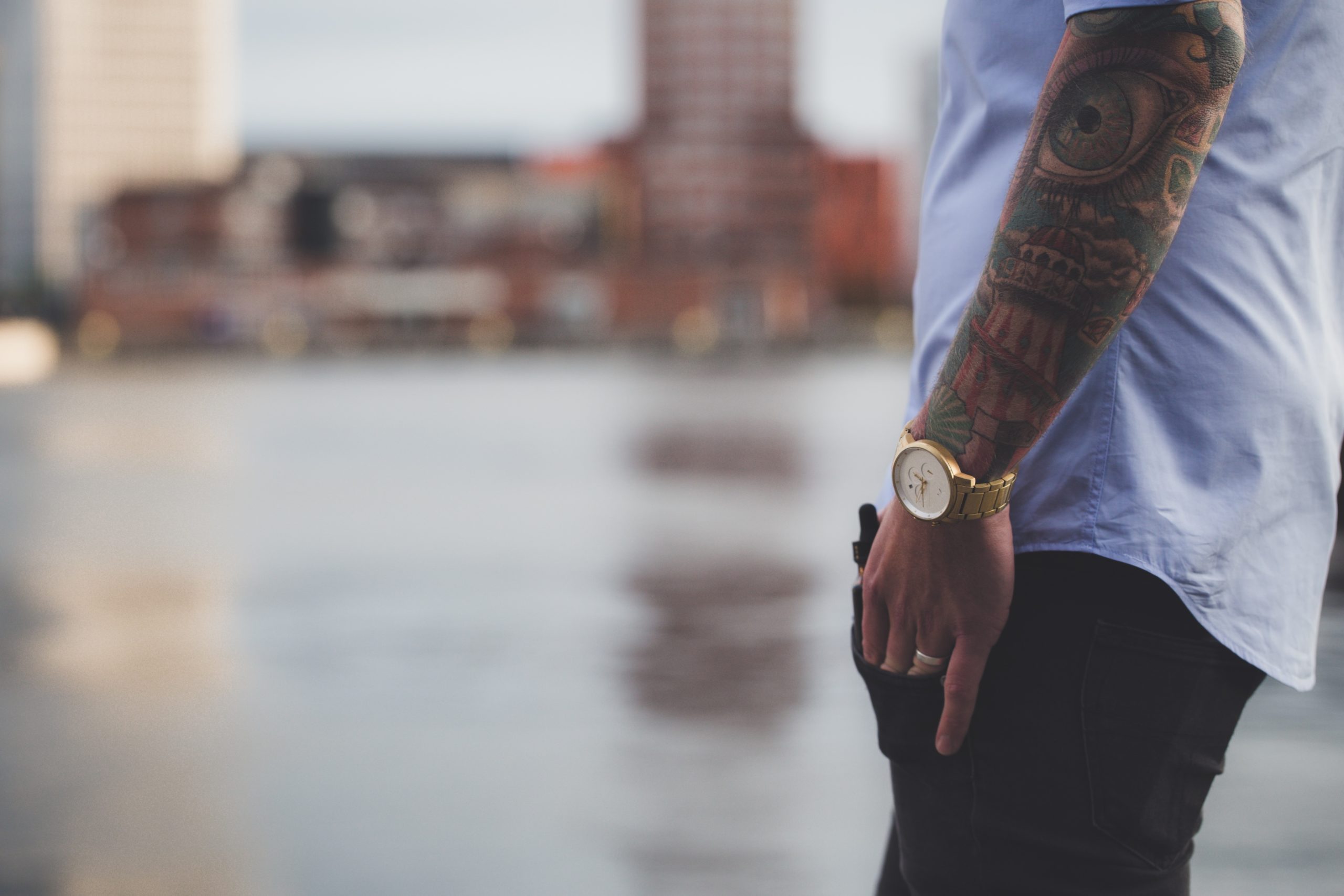 A torso shot of a man with a gold wristwatch on.