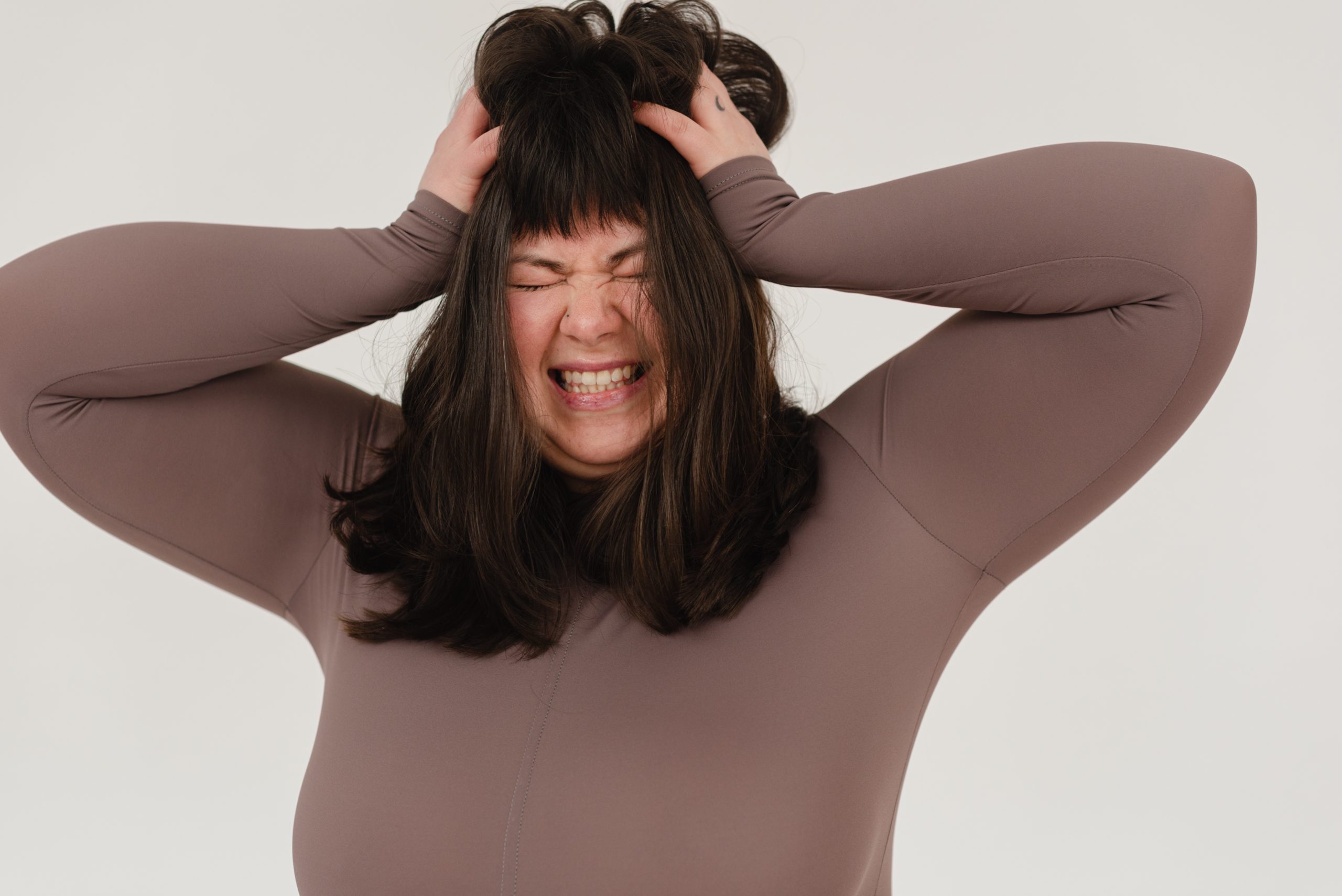 A woman with her hands in her own hair, looking frazzled or angry.