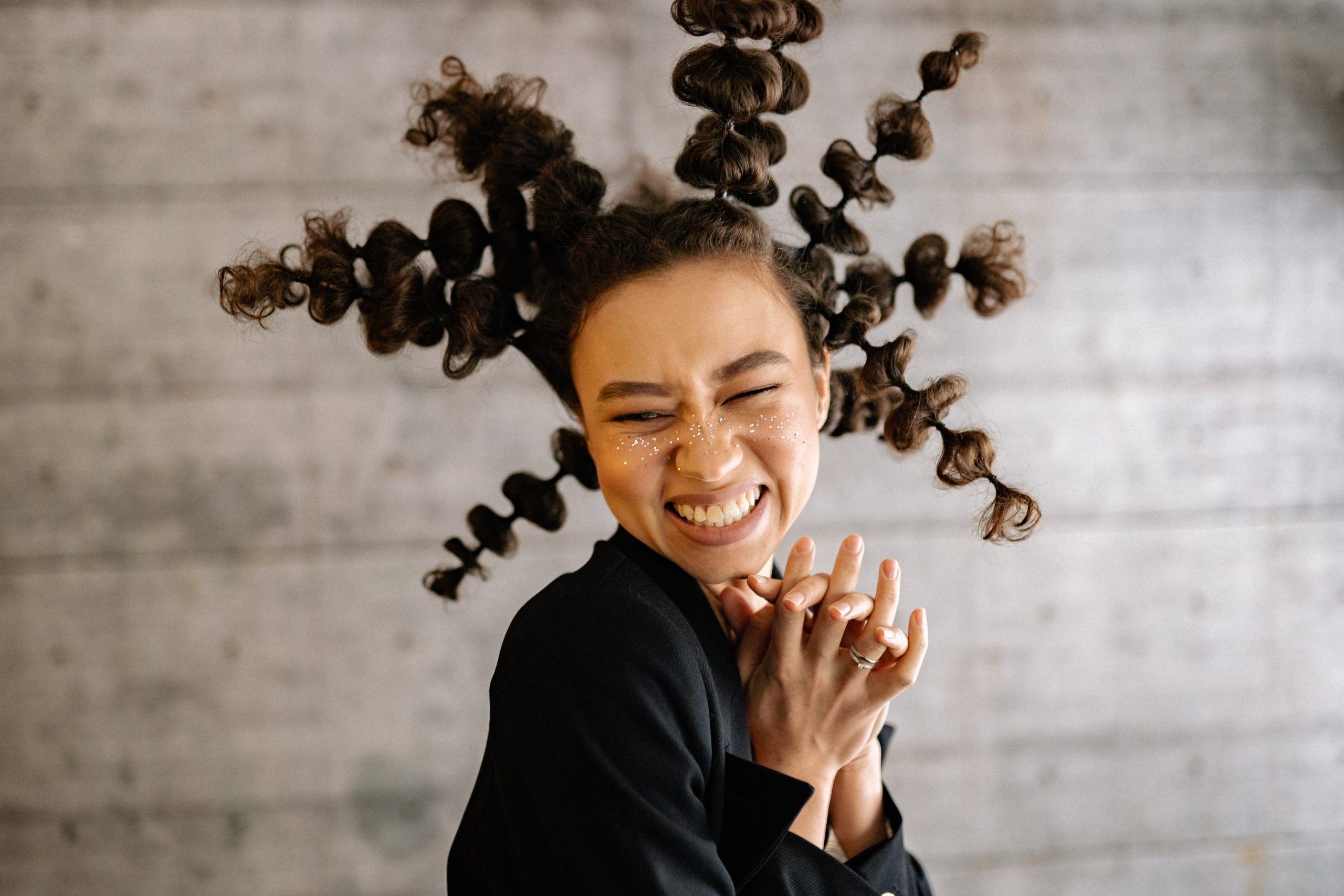 A woman with a unique, out there hairstyle smiling as she laughs.