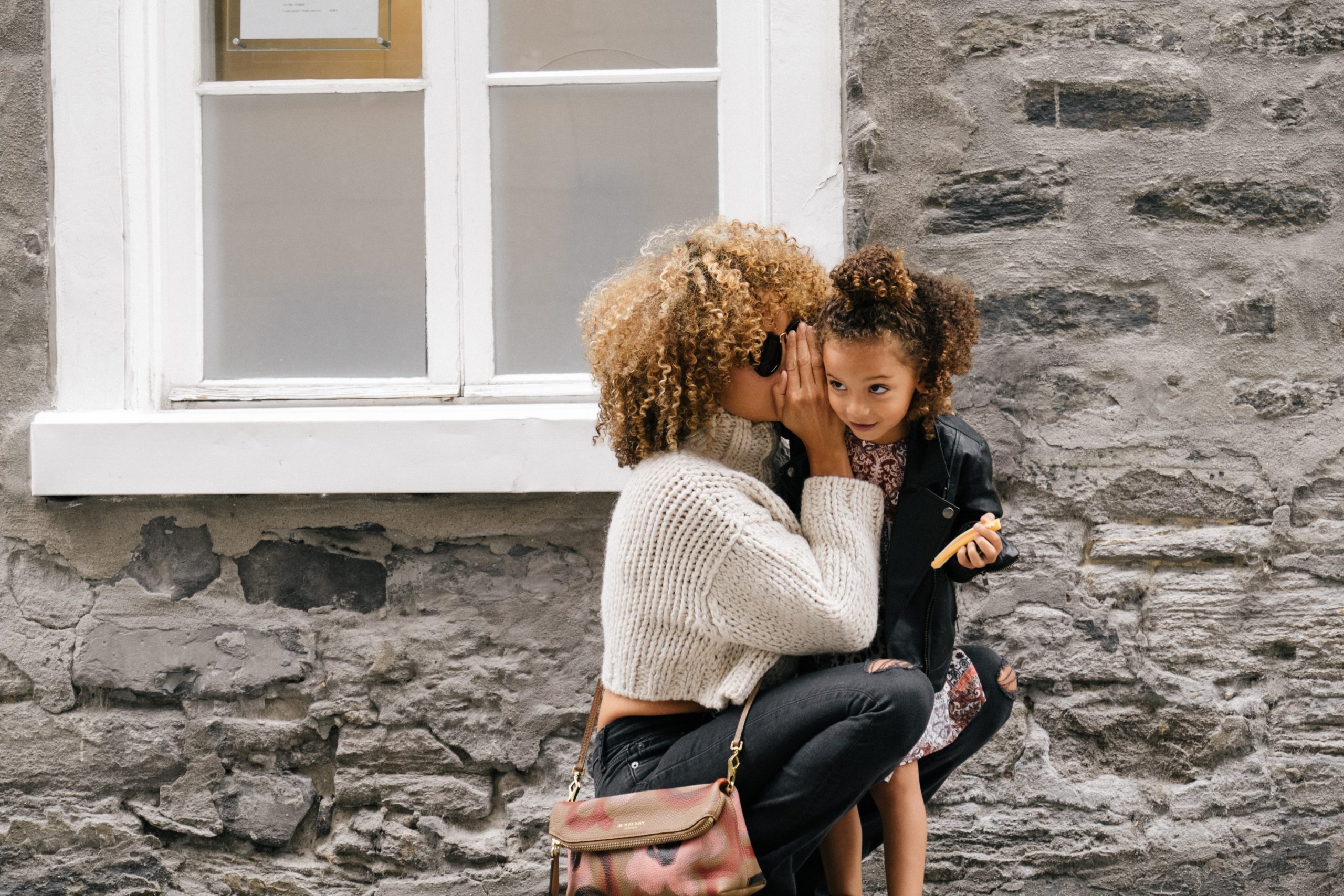 woman whispering into kid's ear