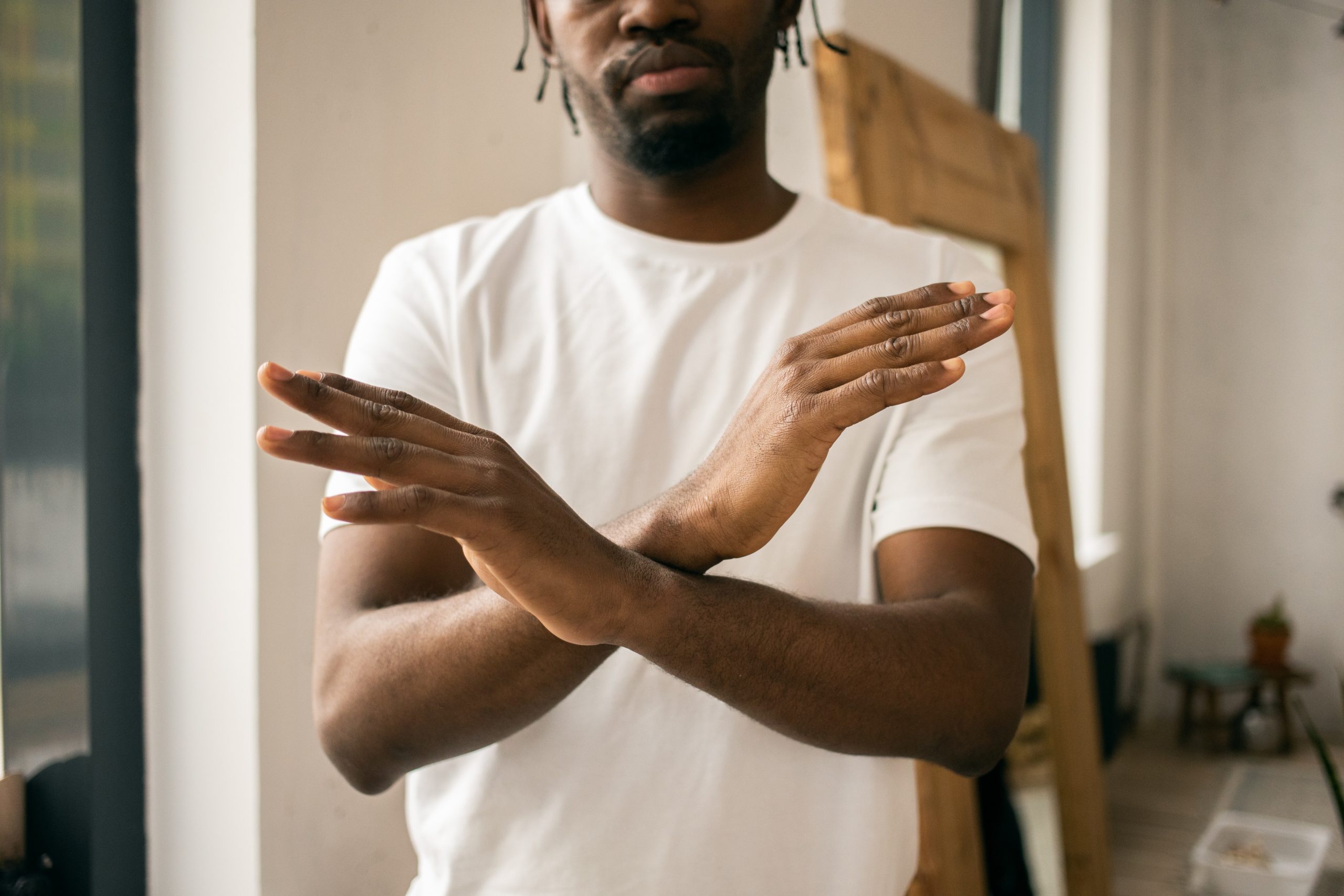 A man standing with his arms crossed in an X in front of his torso.