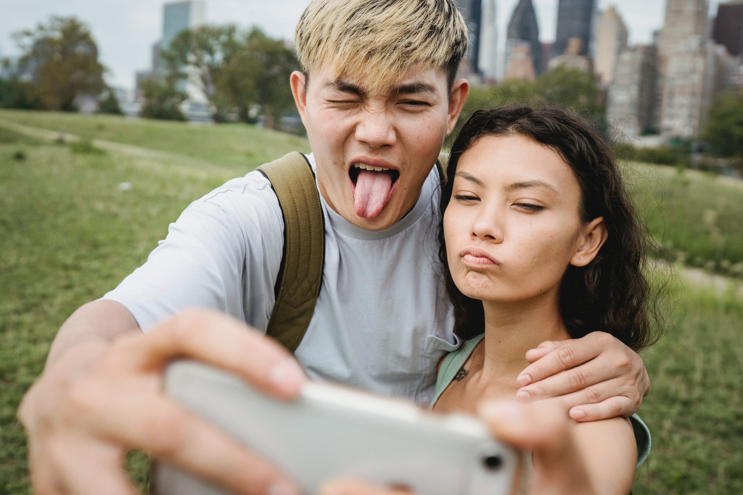 A couple taking a selfie outside, both making silly faces.