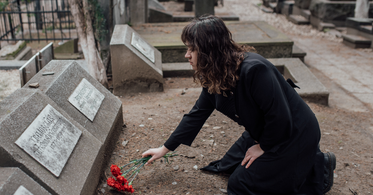 woman at a grave putting flowers down
