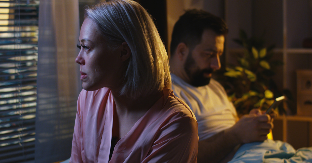 woman crying beside man on his phone