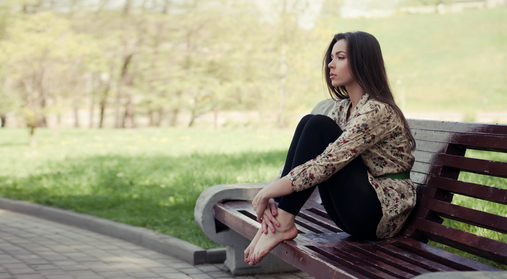 woman sits on park bench with her feet up