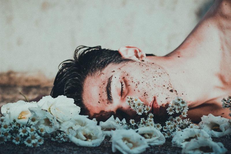 man laying in dirt on a bed of flowers