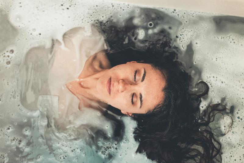 woman emerging in bubble bath fully clothes