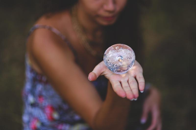 woman holding water bubble in the palm of her hand