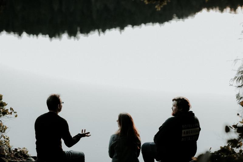 three people talking by the water