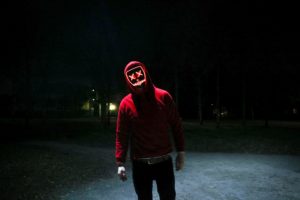 Man in a hoodie and mask at night