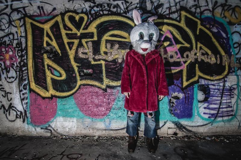 man in rabbit suit standing by graphic wall