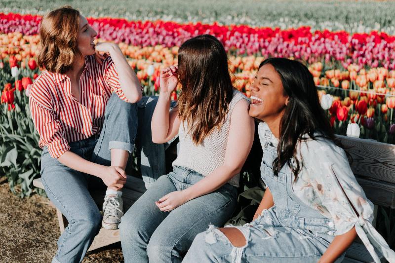 Three women laugh on bench