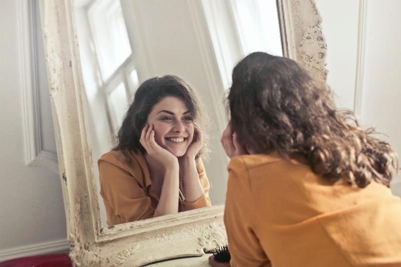 Woman smiling to herself in the mirror.