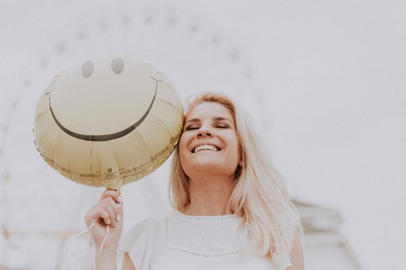 woman smiling beside balloon with smiley face